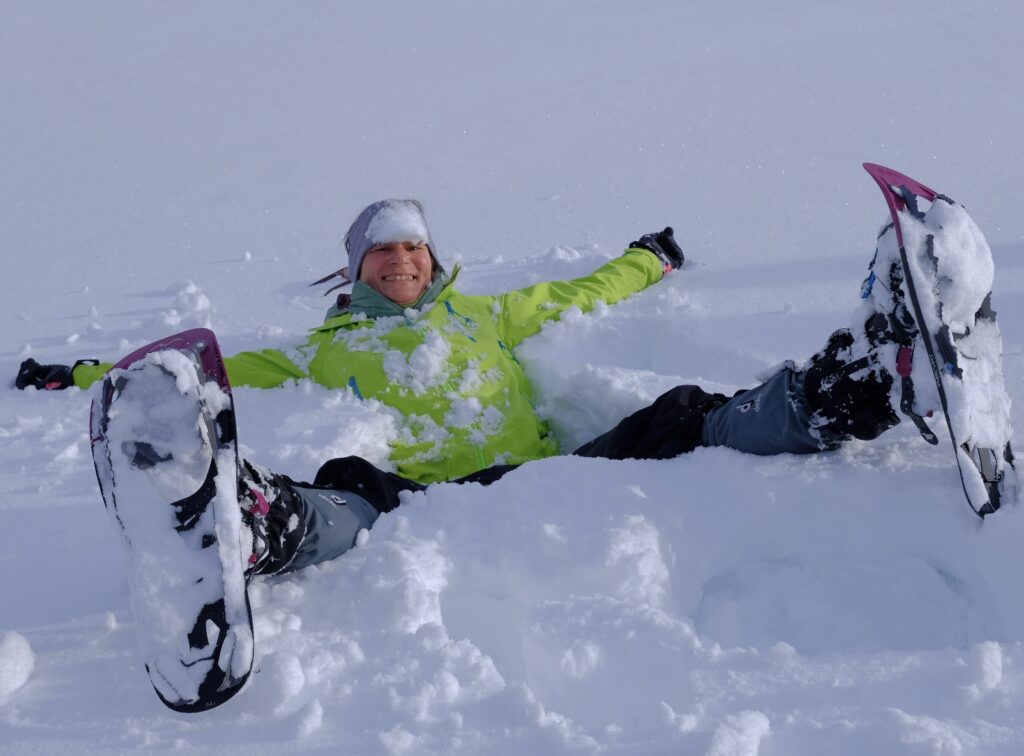 Vicki liegt mit Schneeschuhen im frischen Schnee